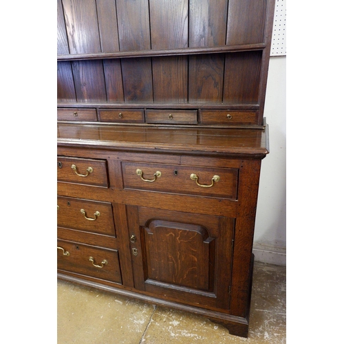 1023 - A part Georgian oak dresser with later back, the base with three frieze drawers over two cupboards a... 