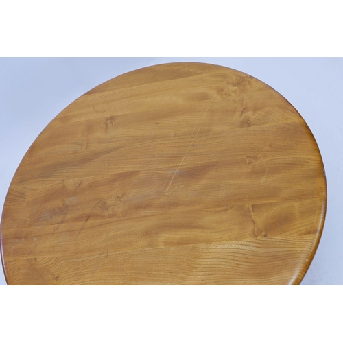 1034 - An Ercol light elm coffee table on four supports united by cross stretcher, 90cm diameter