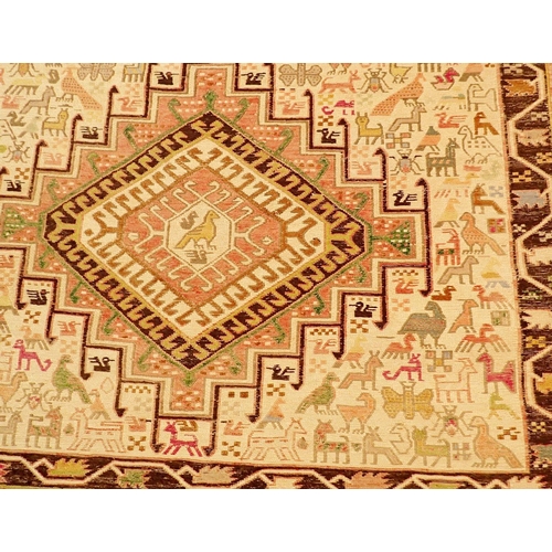 1043 - A Turkish rug with cream ground decorated animals and two lozenges, 210 x 120cm