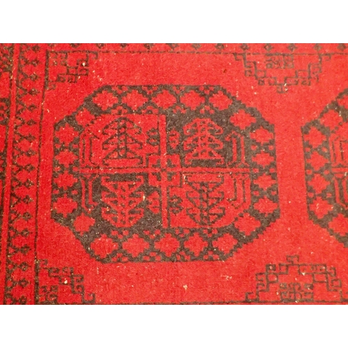 1096 - A Turkoman red wool rug with two blue guls 124 x 80cm