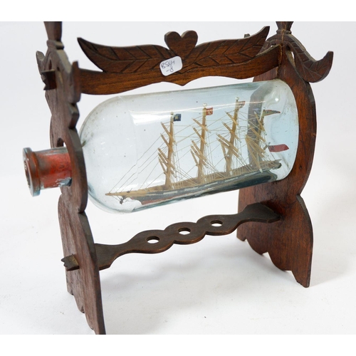 1258 - A vintage small ship in a bottle on carved wooden stand, 21cm long