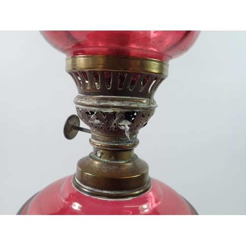 1314 - A Victorian silver plated on copper oil lamp with cranberry glass base, reservoir and shade, 54cm