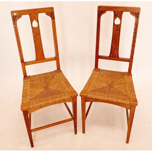 1331 - A pair of Arts & Crafts oak rush seated chairs with pierced leaf to splat