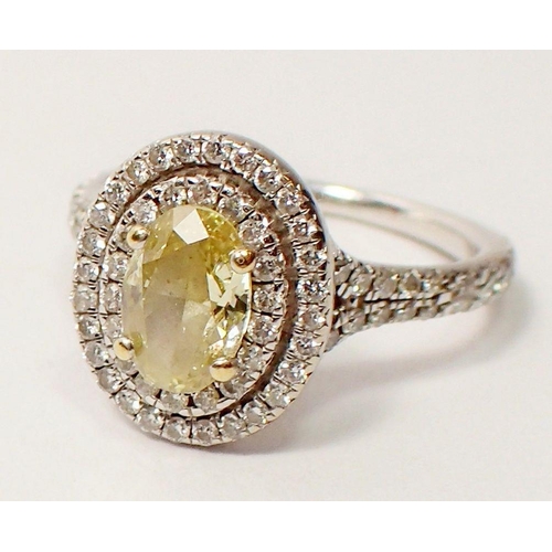 430 - An 18 carat white gold ring set oval yellow diamond within double row of small white  diamonds, size... 