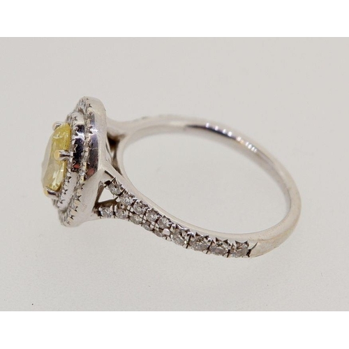 430 - An 18 carat white gold ring set oval yellow diamond within double row of small white  diamonds, size... 