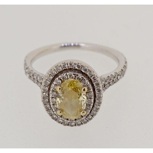 430 - An 18 carat white gold ring set oval yellow diamond within double row of small white  diamonds, size... 