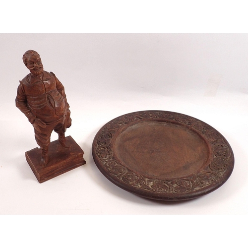 781 - A Black Forest carved wooden figure of a man, 20cm tall and a carved wooden plate