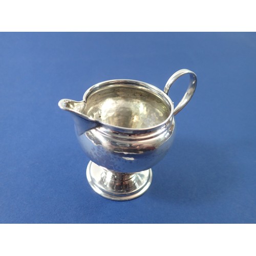 387 - An Arts & Crafts silver hammered cream jug, Birmingham 1909 by Liberty & Co. 46g, 7.5cm