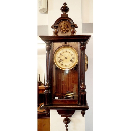 1206 - A 19th century mahogany cased small wall clock with mask to surmount, 72cm tall