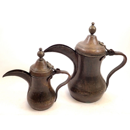 755 - A graduated pair of Dallah Arabic Eastern coffee pots, largest 27cm high, pin hinge missing on large... 