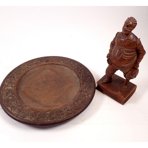 848 - A Black Forest carved wooden figure of a man, 20cm tall and a carved wooden plate