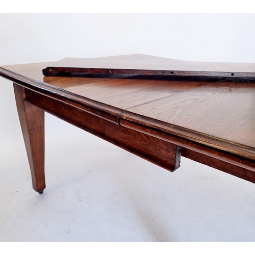 1092 - An Edwardian oak dining table with two interleaves all on tapered supports, the wind out mechanism n... 