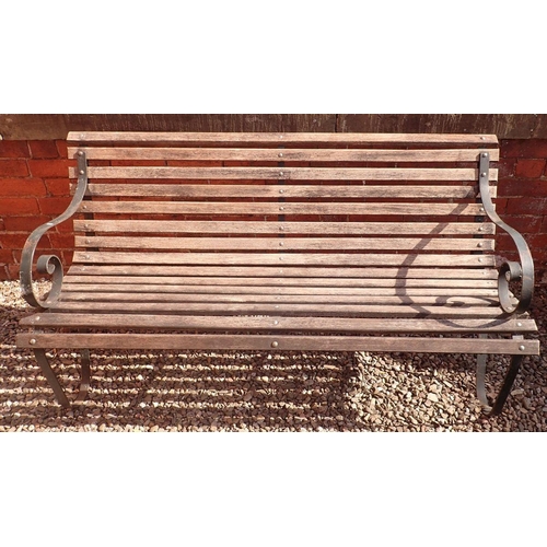 1199 - A garden bench with slatted wooden seat and scrolled cast iron ends, 153cm wide