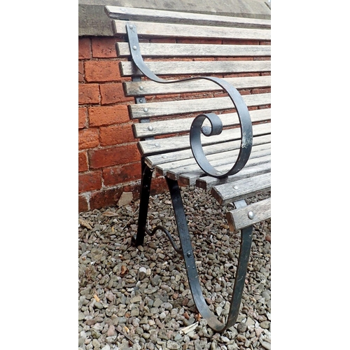 1199 - A garden bench with slatted wooden seat and scrolled cast iron ends, 153cm wide