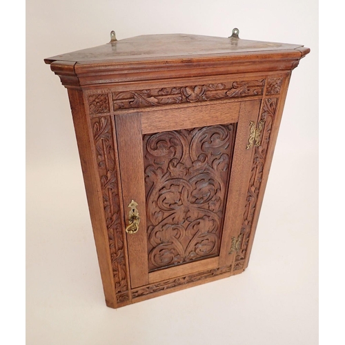 882 - An oak corner cupboard with carved scrollwork decoration to door