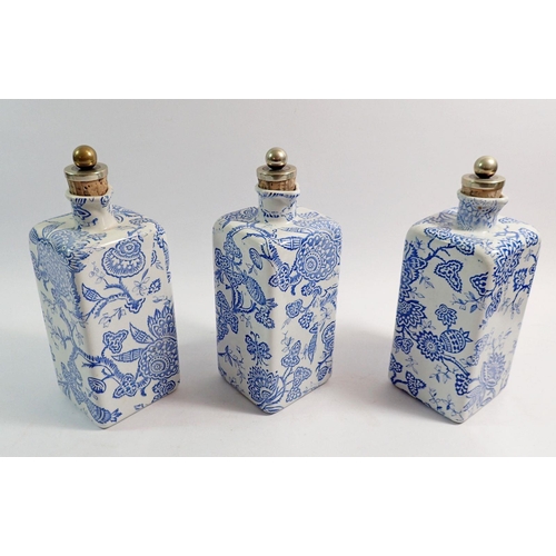 105 - A Victorian set of three blue and white pottery decanters with cork and metal stoppers, all in wicke... 