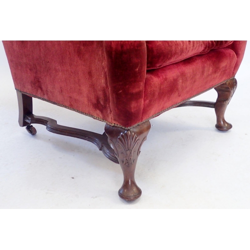 1153 - A George I style wing armchair with cabriole supports united by flat stretchers