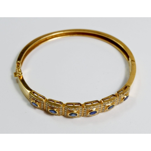 425 - An 18 carat gold hinged bangle with six square panels set sapphires within diamond surround, total w... 