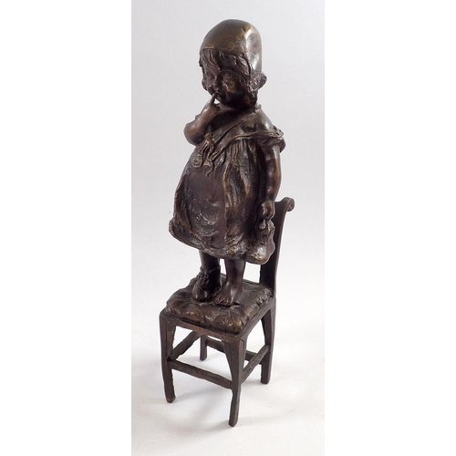 863 - A bronze figure of a child standing on a chair, 31cm tall