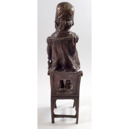 863 - A bronze figure of a child standing on a chair, 31cm tall