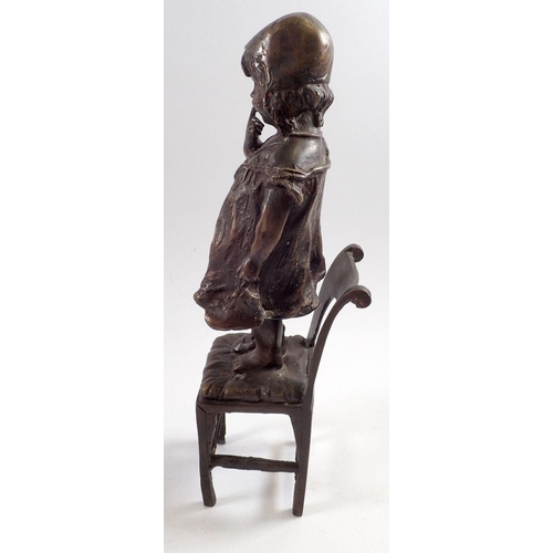 863 - A bronze figure of a child standing on a chair, 31cm tall