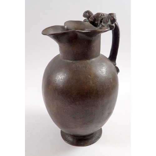 867 - A 19th century bronze jug in Roman style with lions head and anthemon leaf handle, 25cm tall