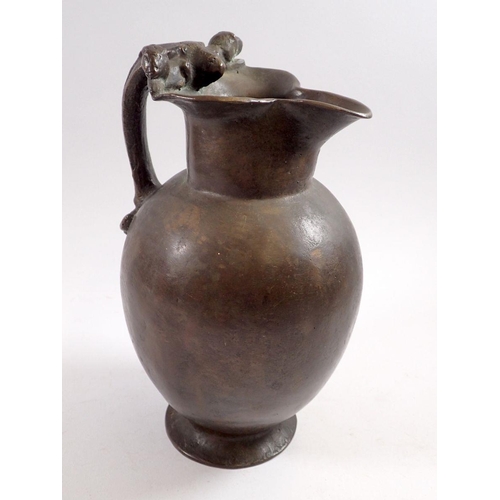 867 - A 19th century bronze jug in Roman style with lions head and anthemon leaf handle, 25cm tall