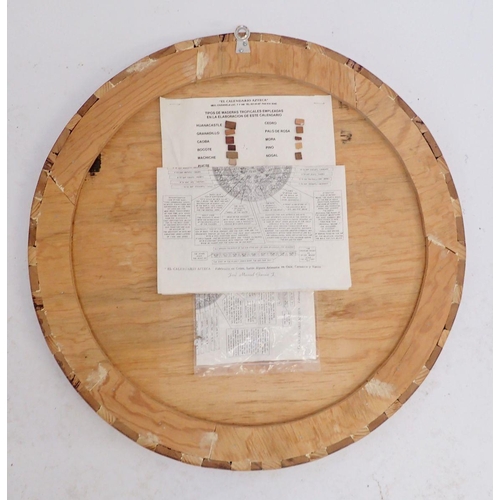 928 - A marquetry Aztec calendar with paperwork, 53.5cm diameter