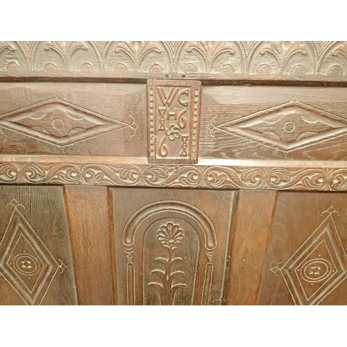 1055 - A 17th century oak four panel settle with carved decoration and dated 1661, 121cm x 185cm wide x 55c... 