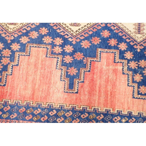 1091 - A large Persian rug with geometric and floral design on a pink ground, 214 x 162cm