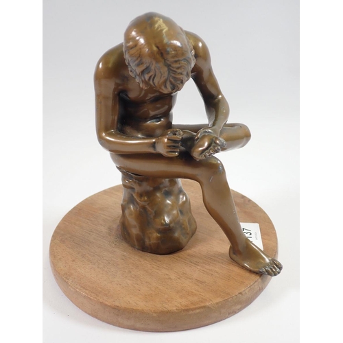 1137 - A bronze finish figure of man removing thorn from his foot on later base, 19cm tall