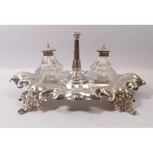 323 - A Victorian silver inkstand with leaf clad taper stick flanked by two cut glass inkwells, the stand ... 