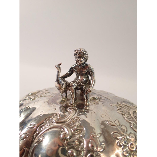 335 - A continental silver fluted oval box with putti and peacock finial and all over embossed scrollwork ... 