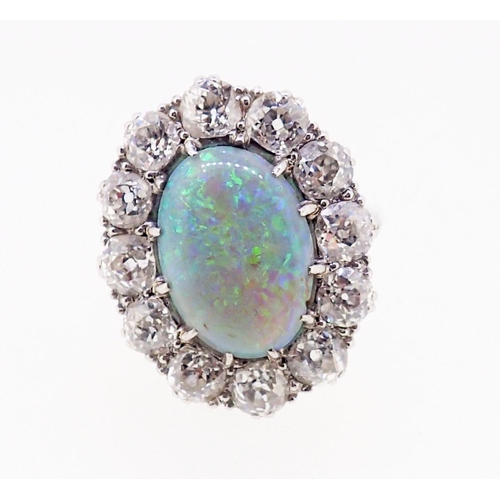 389 - A large platinum opal and diamond cluster ring, the opal 12mm x 9mm, the twelve brilliant cut diamon... 