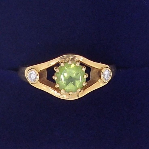 399 - An 18 carat gold ring set peridot flanked by a pair of diamonds, size N, 6.5g