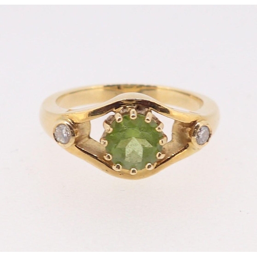 399 - An 18 carat gold ring set peridot flanked by a pair of diamonds, size N, 6.5g