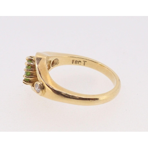 399 - An 18 carat gold ring set peridot flanked by a pair of diamonds, size N, 6.5g