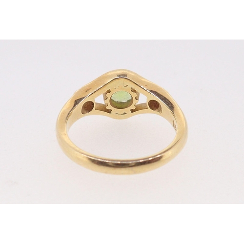 399 - An 18 carat gold ring set peridot flanked by a pair of diamonds, size N, 6.5g