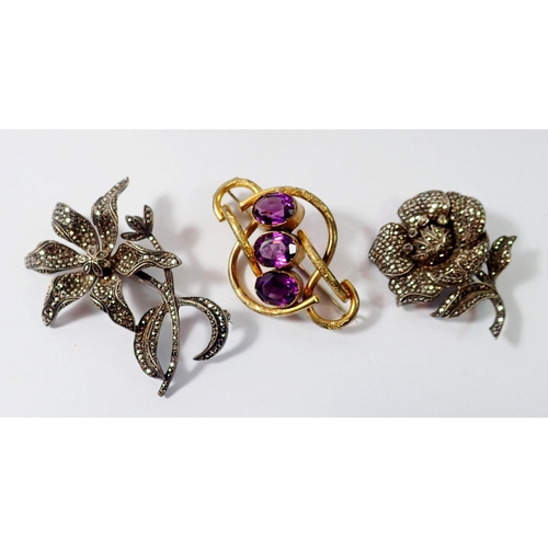 452 - Two silver and marcasite flower form brooches and a Victorian gilt metal and purple glass brooch, 6c... 