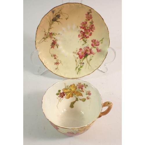 131 - A Royal Worcester cup and saucer painted spray of flowers on ivory blush ground, restored