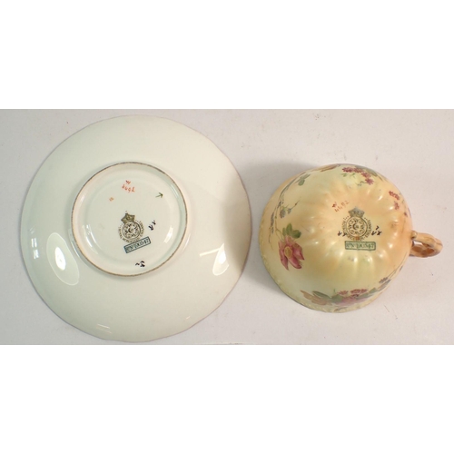 131 - A Royal Worcester cup and saucer painted spray of flowers on ivory blush ground, restored