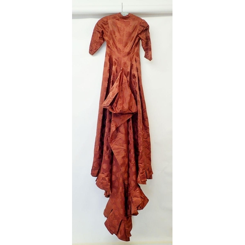 561 - A Victorian russet brown satin silk dress with floral design, button front and long bustle