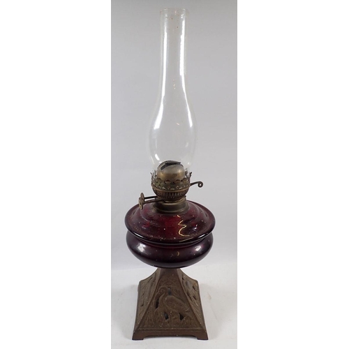 753 - A Victorian oil lamp with red glass reservoir, 55cm tall