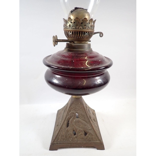 753 - A Victorian oil lamp with red glass reservoir, 55cm tall