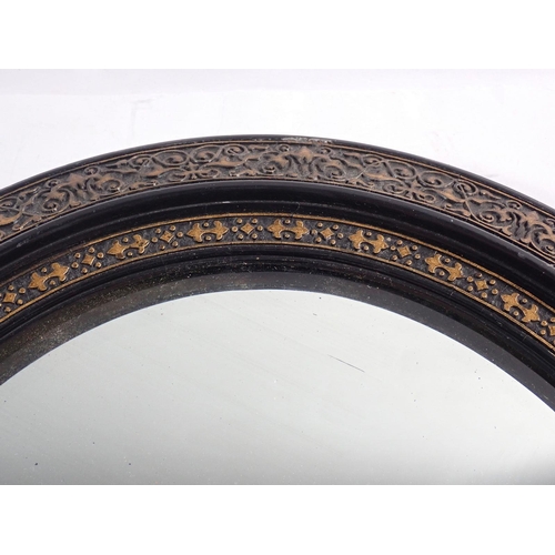 965 - An oval ebonised and gilt framed mirror, 42 x 38cm