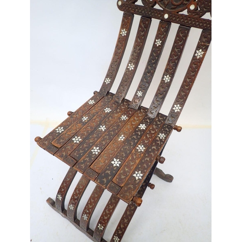 976 - An Islamic teak and mother of pearl folding chair with carved script