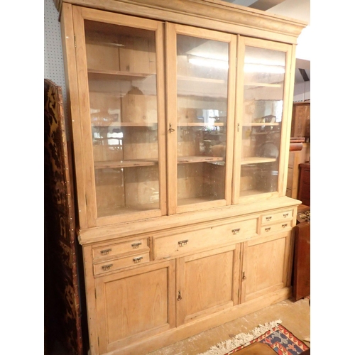 1005 - A large 19th century pine farmhouse cabinet with three glazed doors enclosing shelves over four smal... 