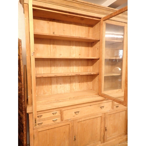 1005 - A large 19th century pine farmhouse cabinet with three glazed doors enclosing shelves over four smal... 