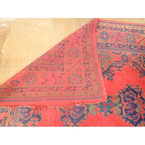 1016 - A large Turkish carpet with blue and green motifs on a red ground, 340 x 368cm