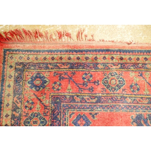 1016 - A large Turkish carpet with blue and green motifs on a red ground, 340 x 368cm